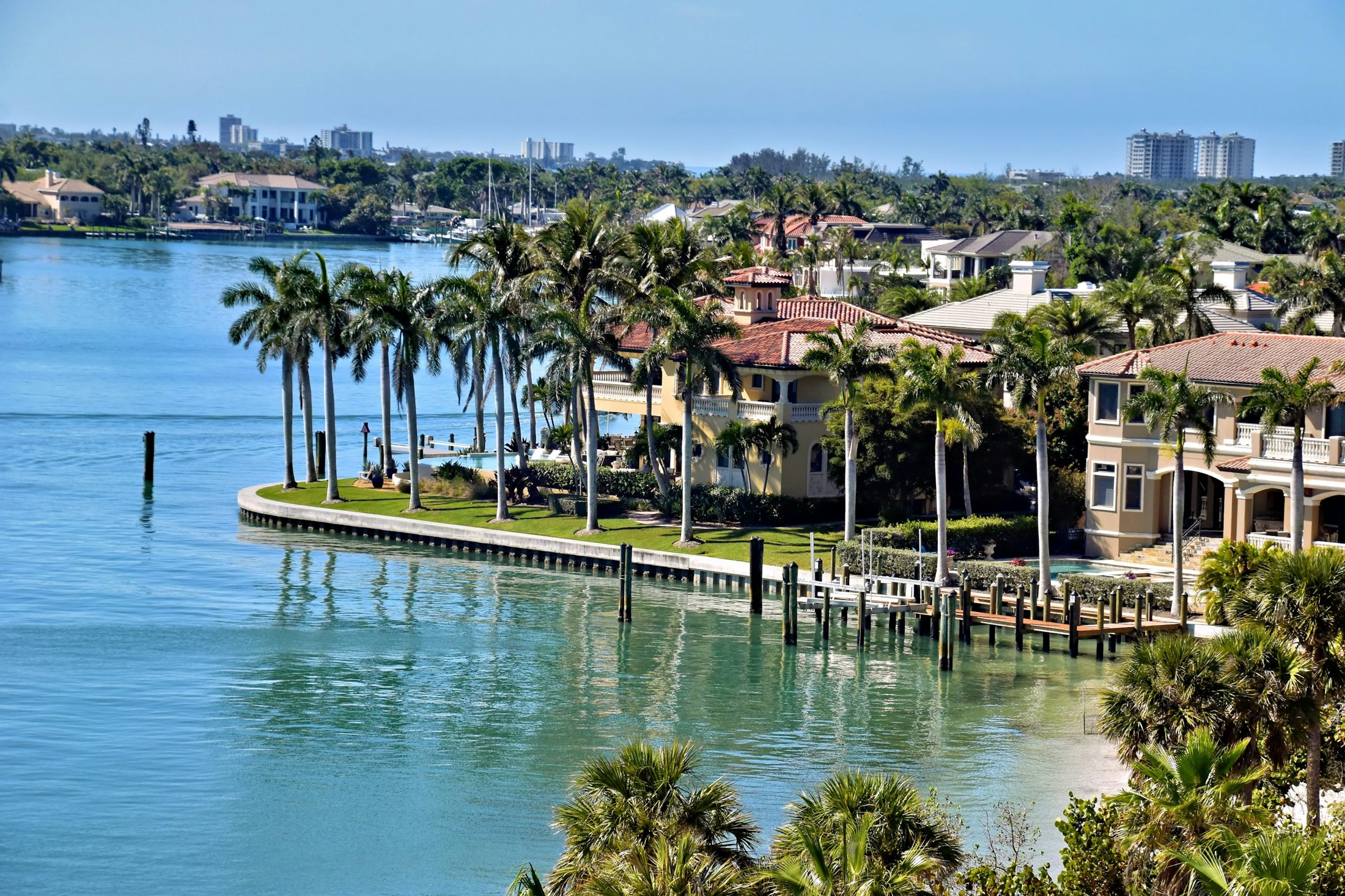 Waterfront residences framed by palm trees along a coastal waterway