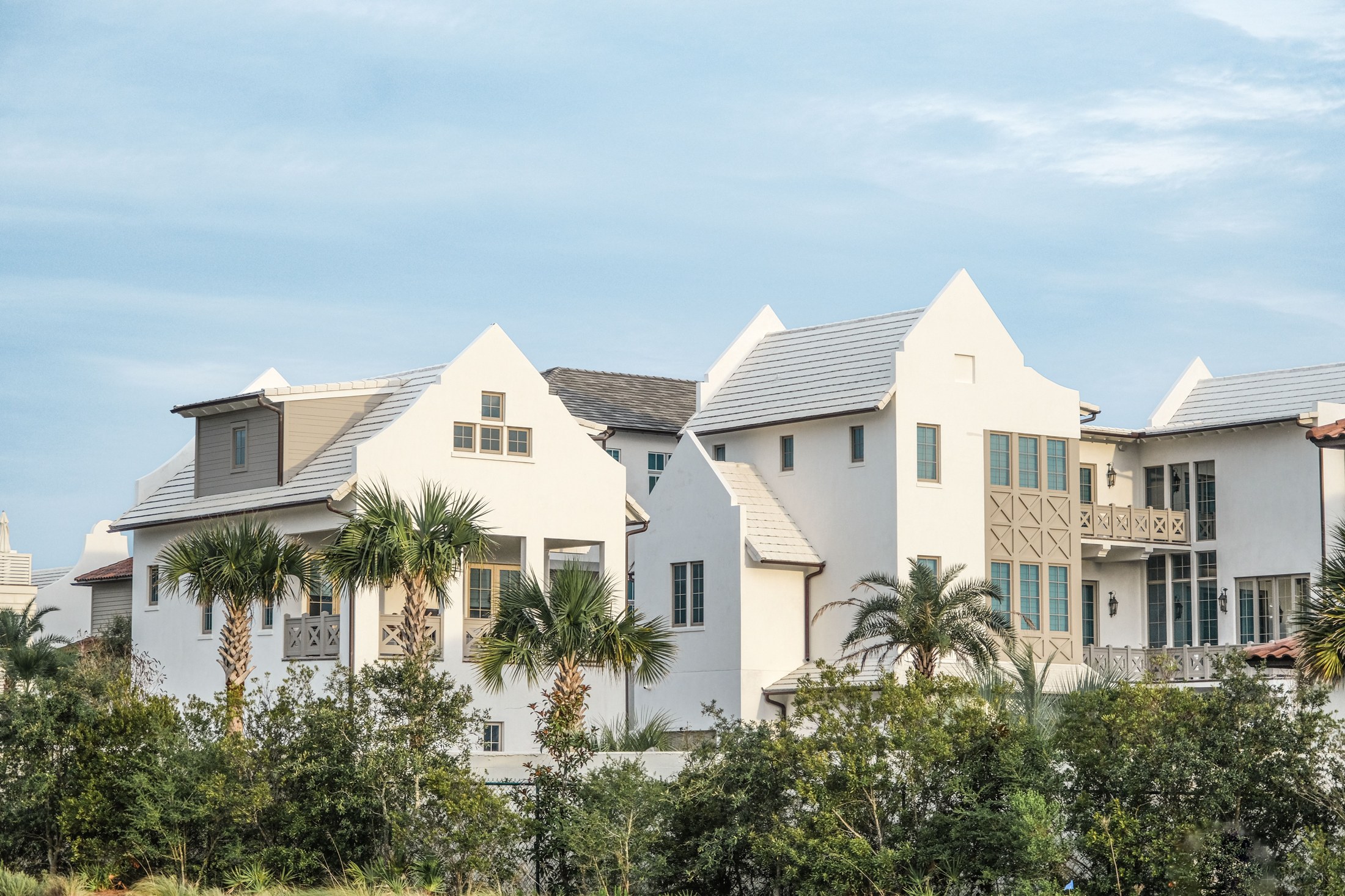 White coastal residences with crisp rooflines and palm landscaping